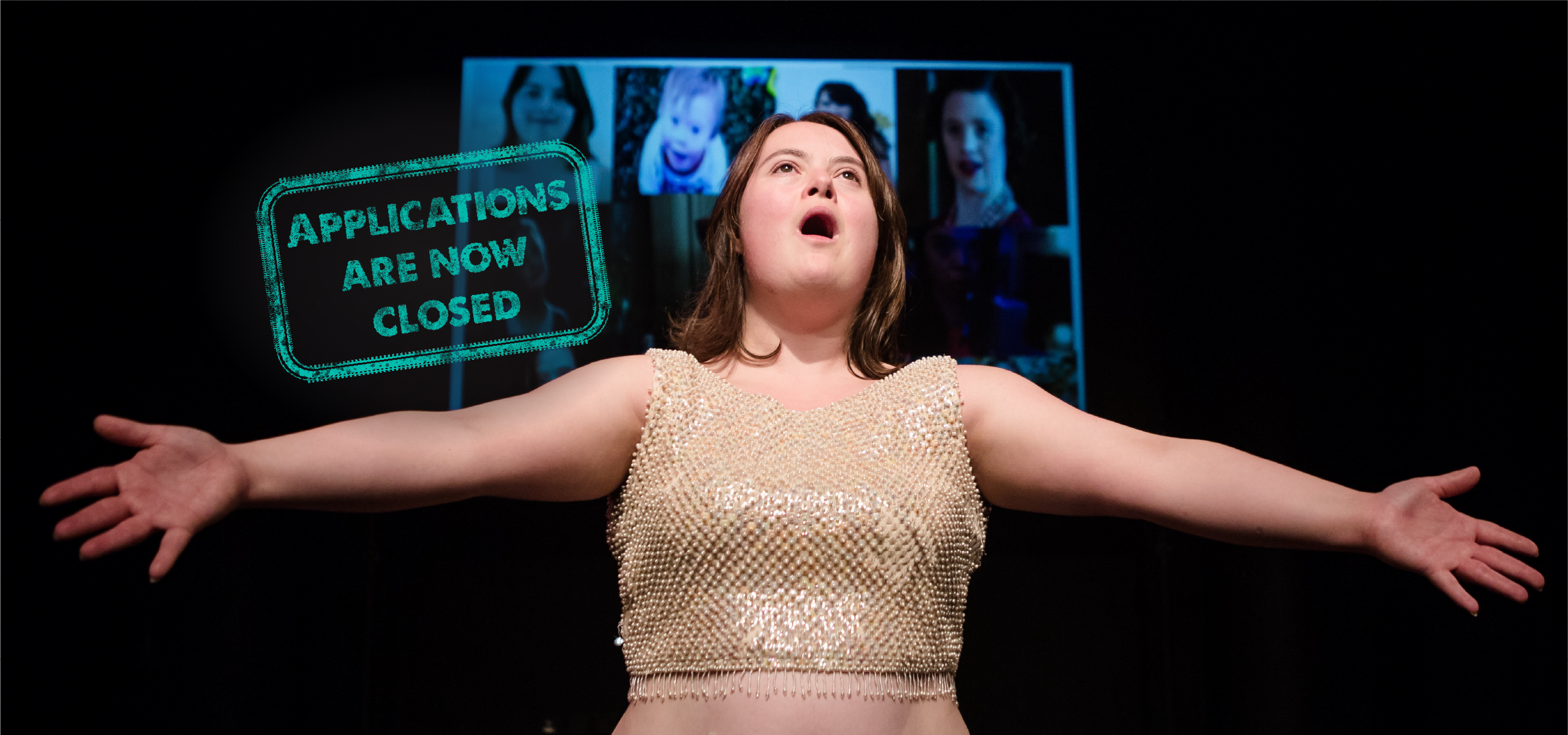 A Diploma Student stand in a dark place. She wears a cream color sequin crop top. She has mid-lenght dark blonde haire. She has her arm spread and her mouth is open as if she was singing. Behind her, projected, a mosaic of muliple portraits of people.